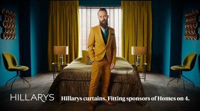 a man in a yellow suit standing in front of a bed