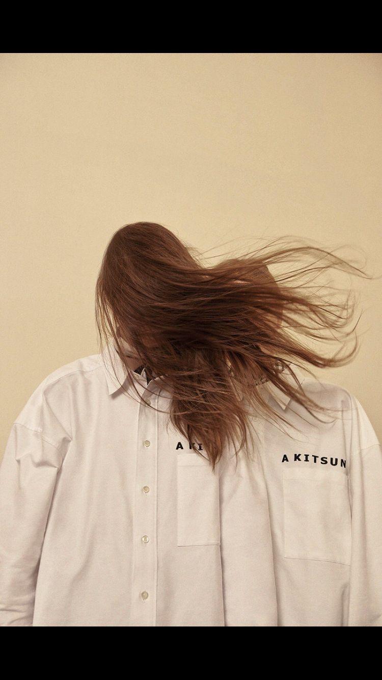 a person with long hair standing in front of a wall
