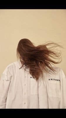 a person with long hair standing in front of a wall