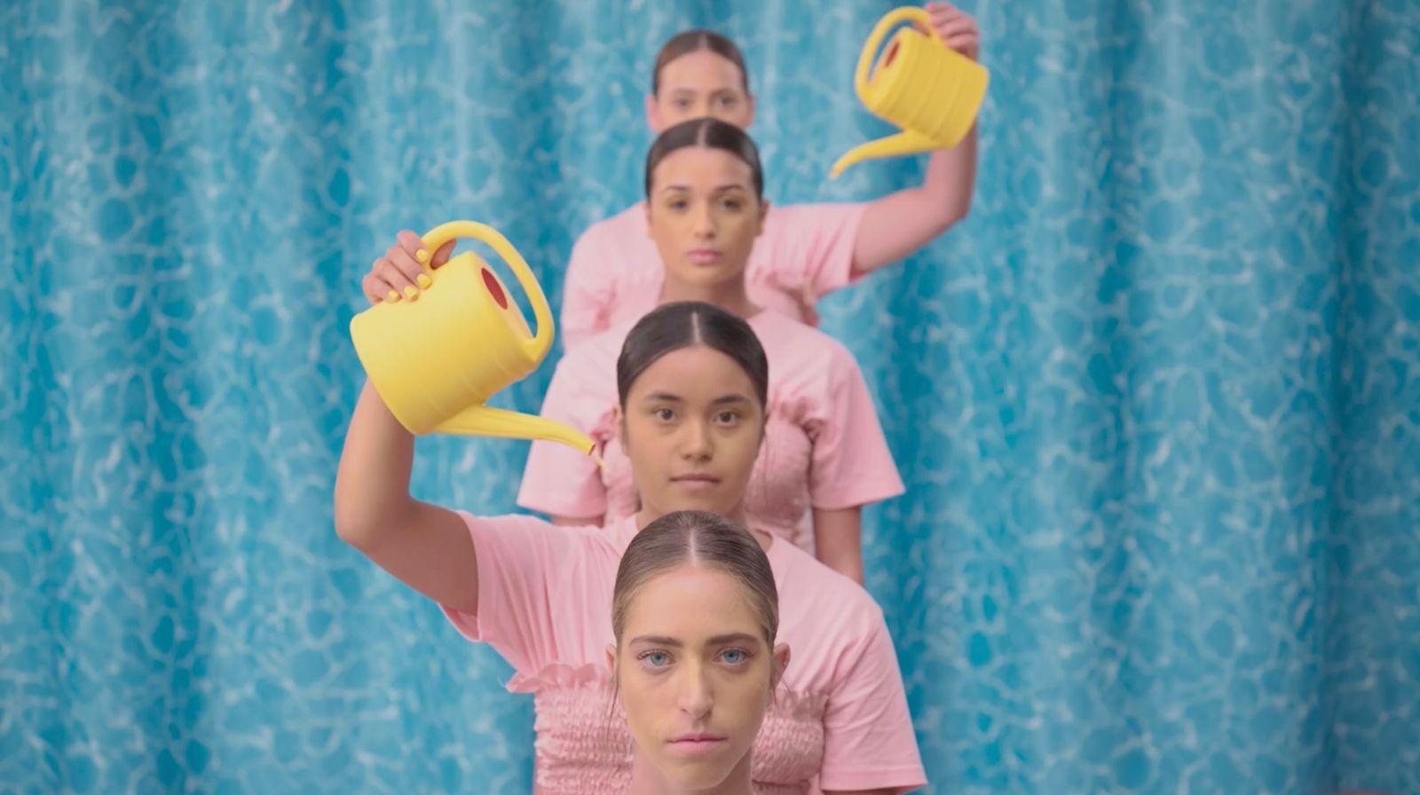 a group of women in pink shirts holding yellow pitchers