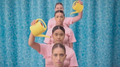 a group of women in pink shirts holding yellow pitchers