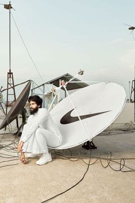 a man sitting on the ground next to a satellite dish