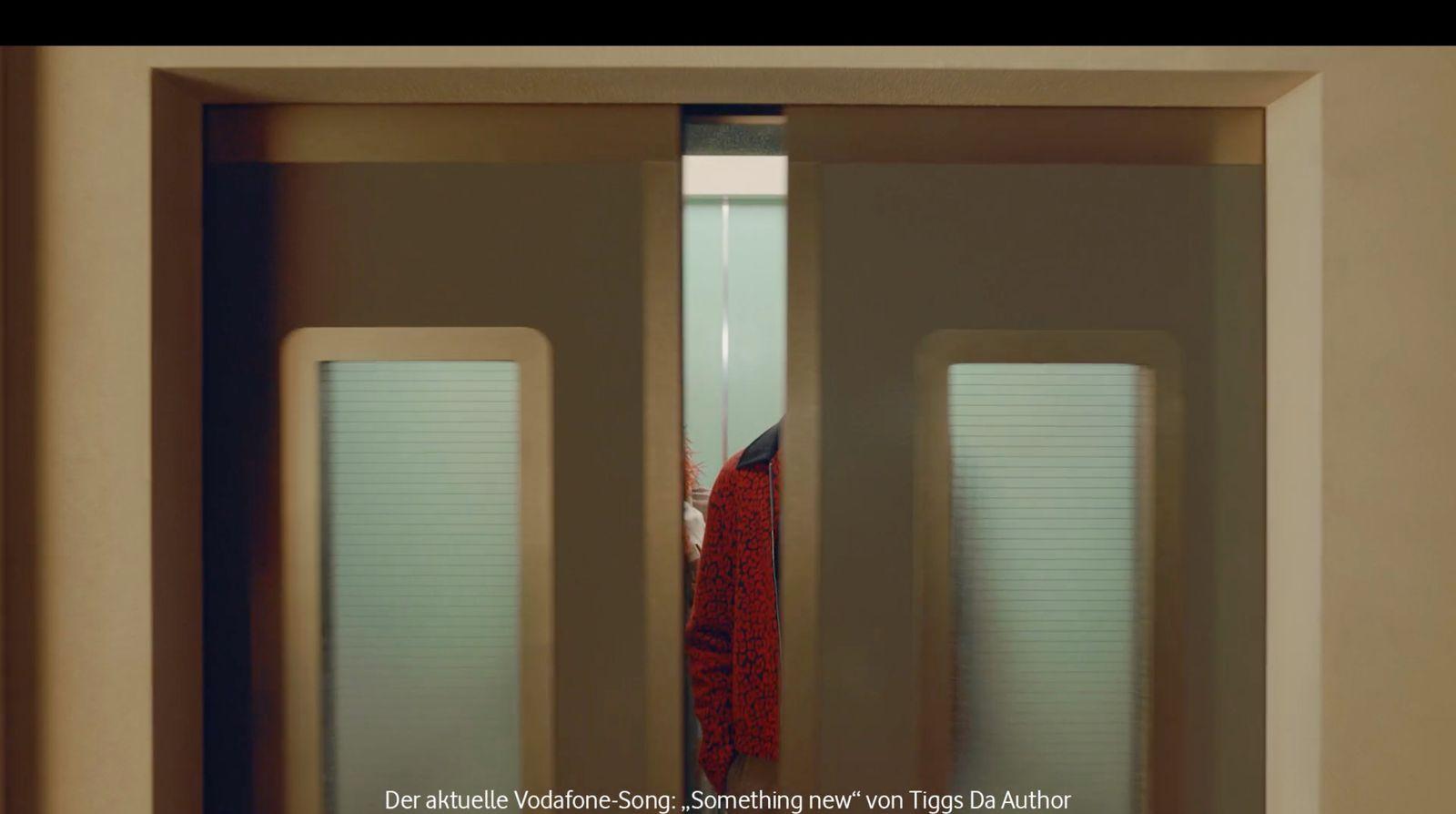 a woman in a red shirt is standing in a doorway