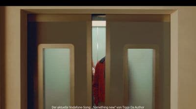 a woman in a red shirt is standing in a doorway