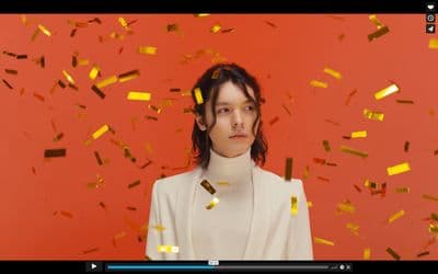 a woman standing in front of a red wall with gold confetti