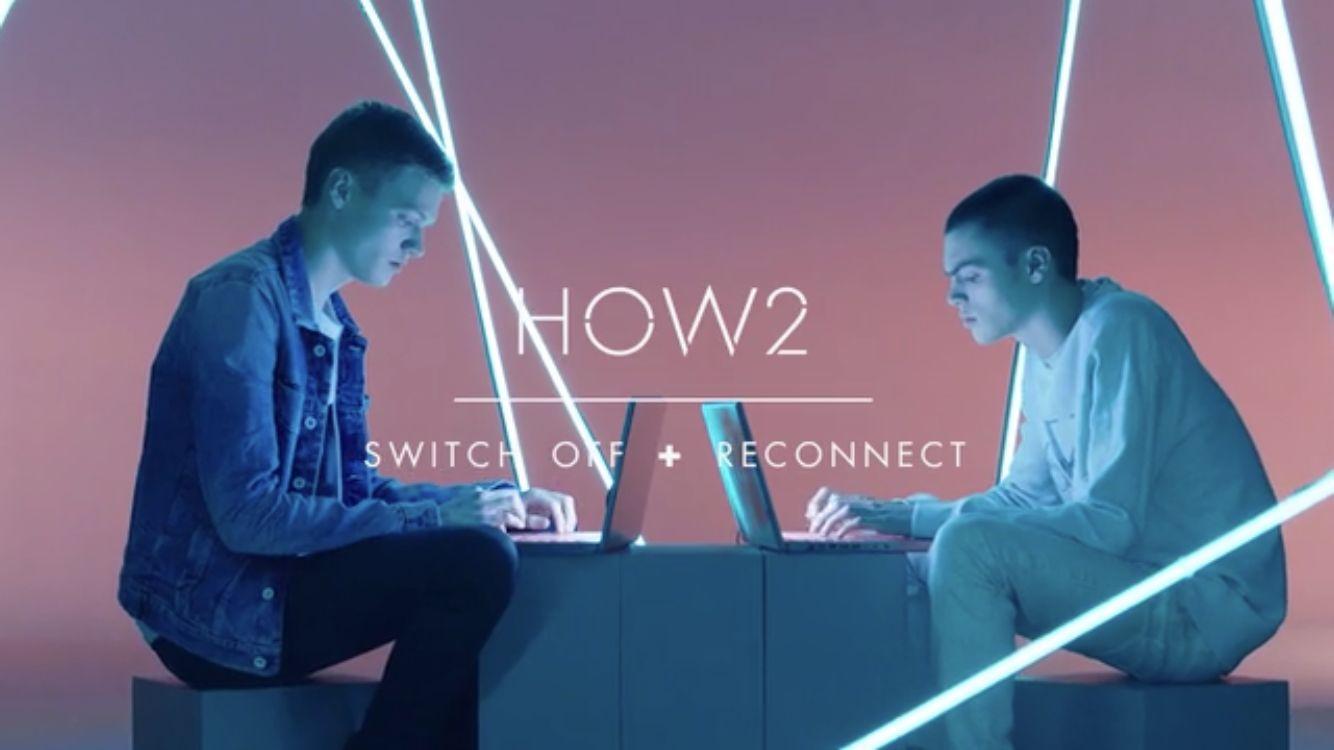 two men sitting on cubes using laptops