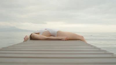 a woman laying on a dock in the water