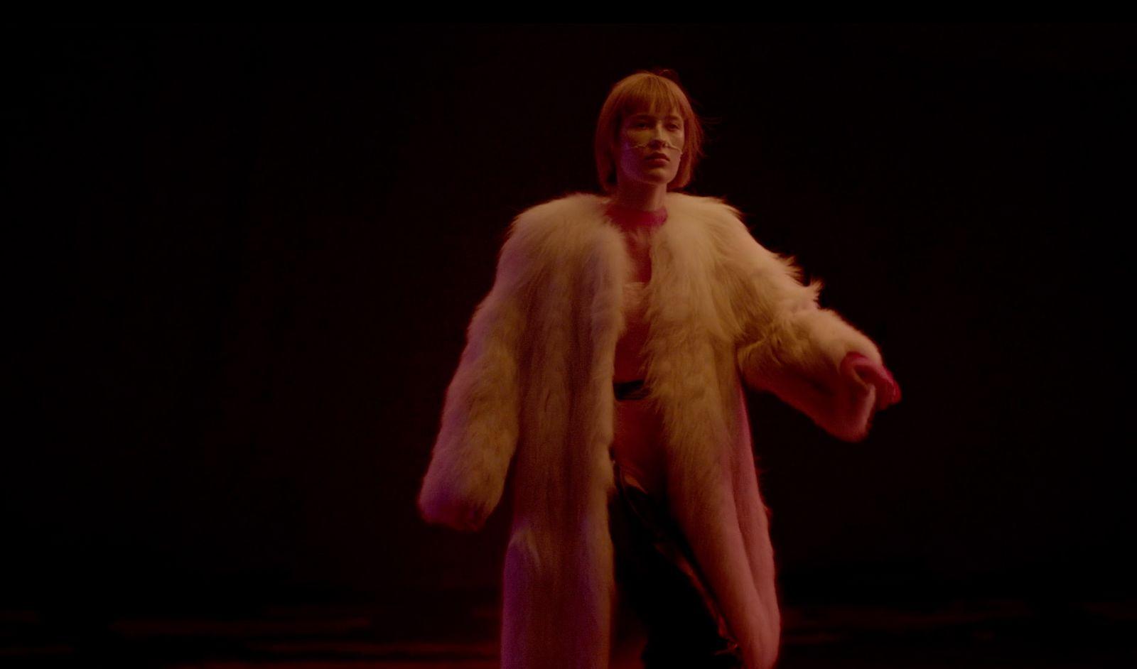a woman in a fur coat is standing in the dark