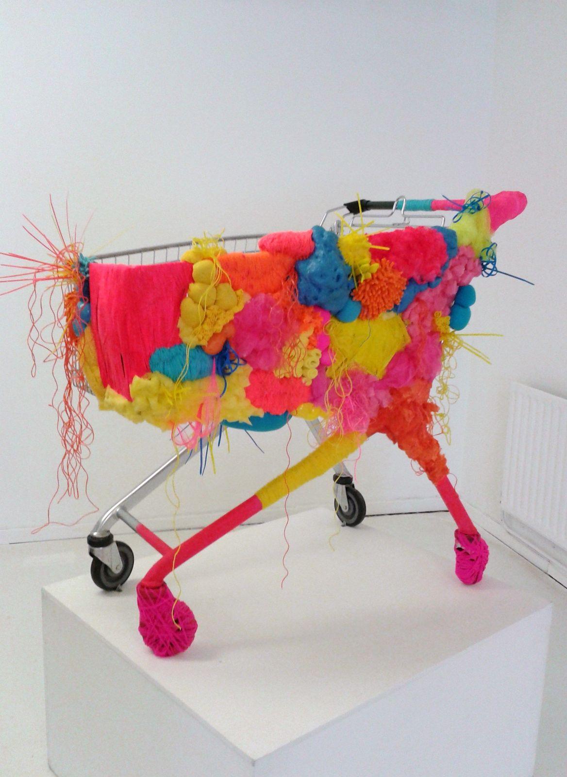 a shopping cart covered in colorful fabric on a white surface