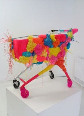 a shopping cart covered in colorful fabric on a white surface