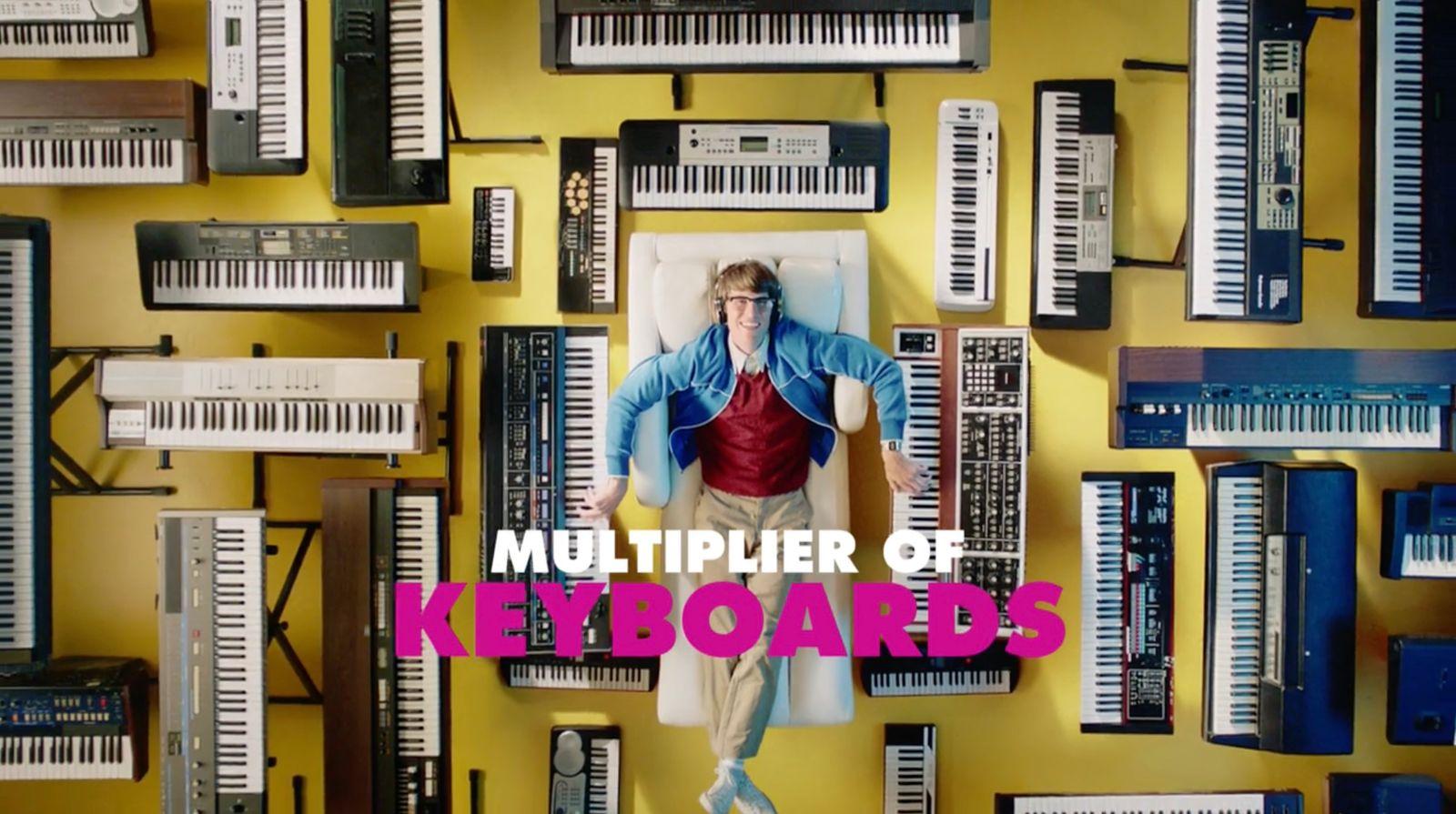 a man standing in front of a wall of keyboards
