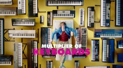 a man standing in front of a wall of keyboards