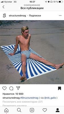 a man sitting on top of a blue and white striped towel