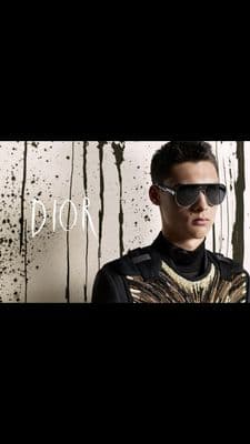 a man wearing sunglasses standing in front of a wall