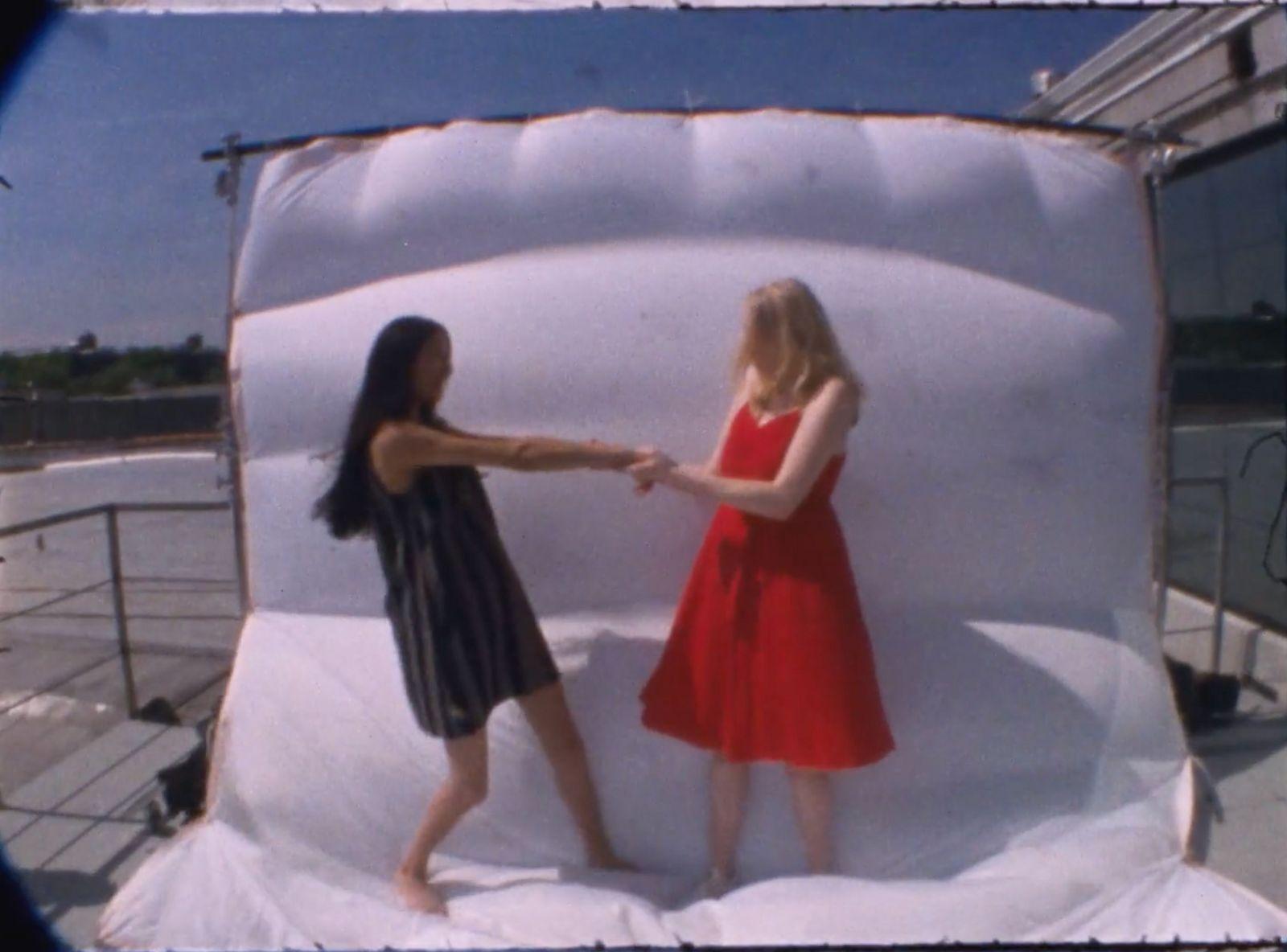 two girls in a red dress standing in front of a white backdrop