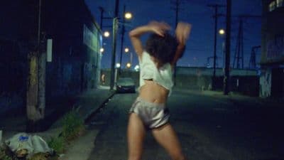 a woman is dancing on the street at night