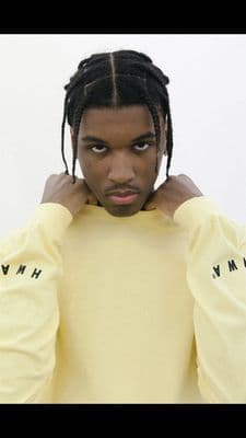 a man with dreadlocks wearing a yellow shirt