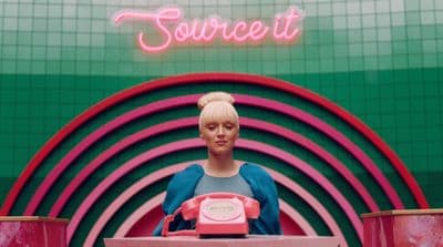 a mannequin holding a pink phone in front of a neon sign