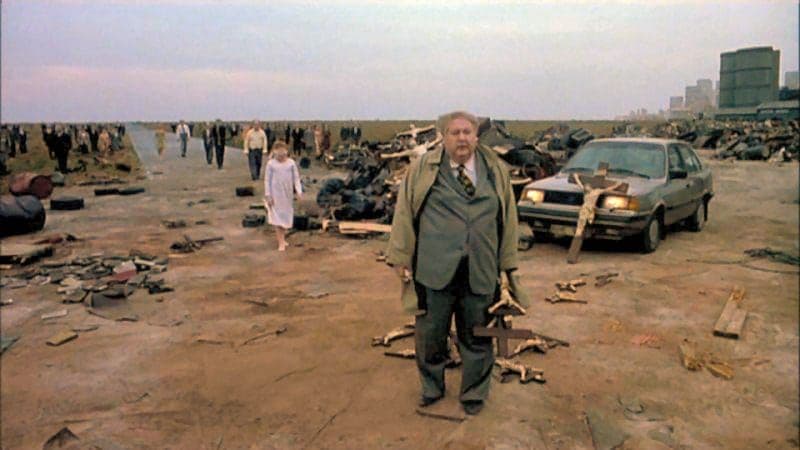 a man standing in front of a bunch of junk
