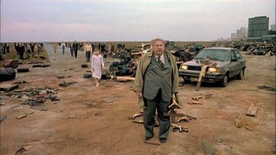 a man standing in front of a bunch of junk