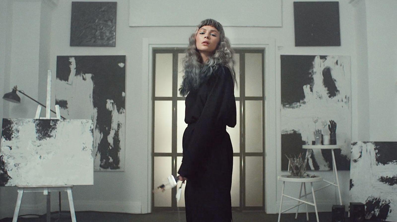 a woman standing in front of a painting in a room