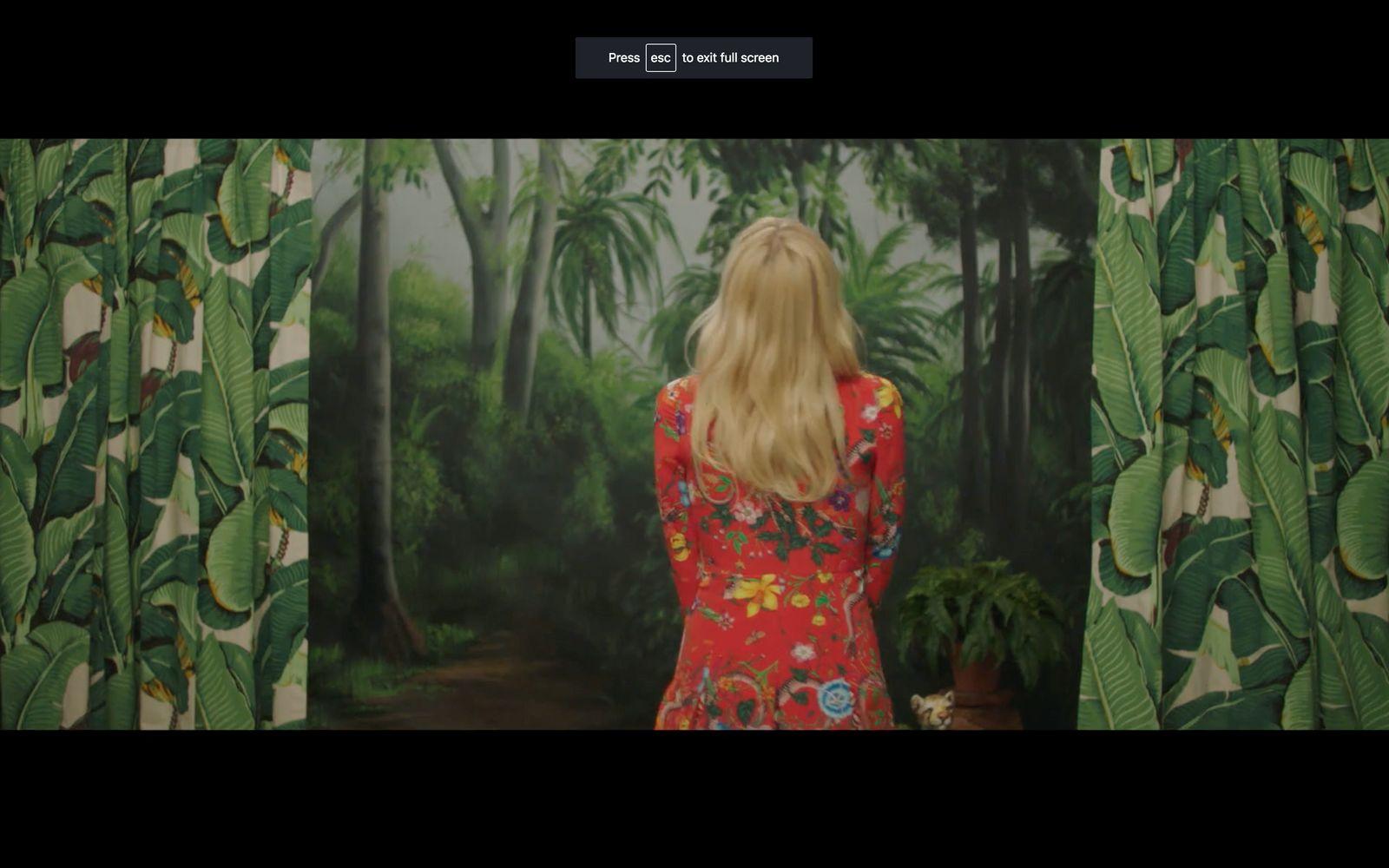 a woman standing in front of a painting of a forest