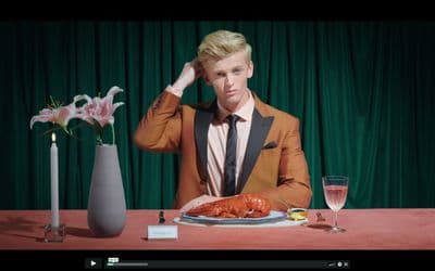 a man sitting at a table with a plate of lobsters