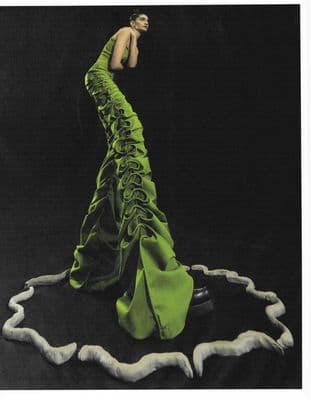 a woman in a green dress standing on a black surface