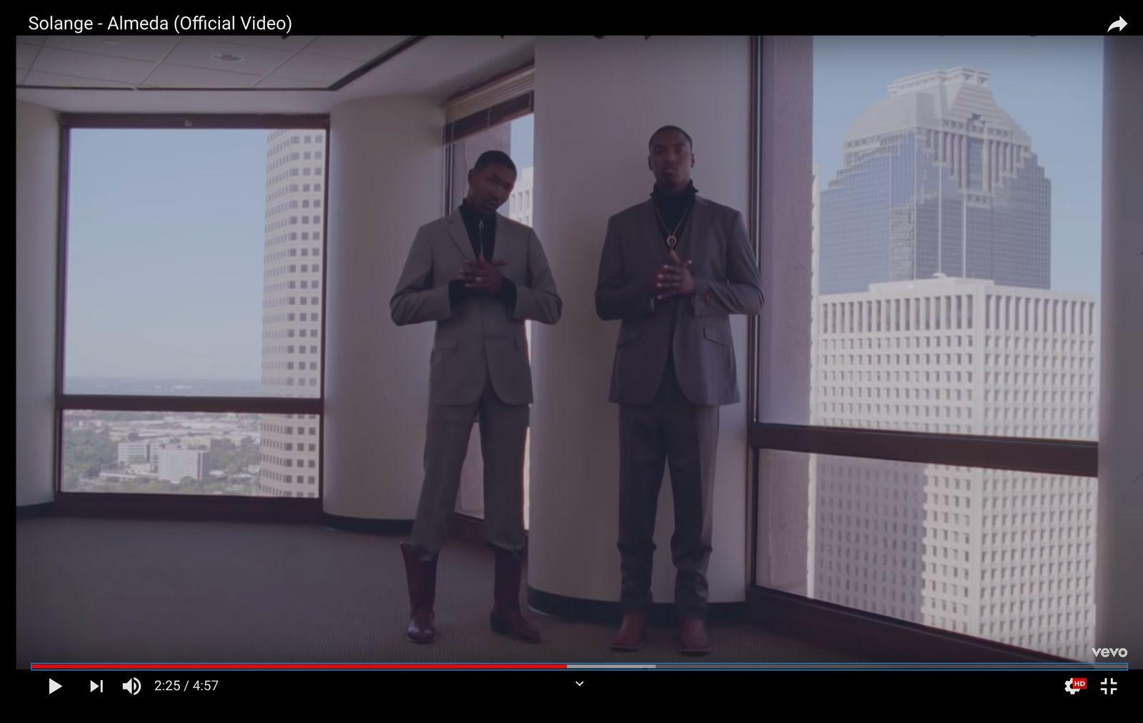 two men in suits standing in front of a window