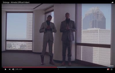 two men in suits standing in front of a window