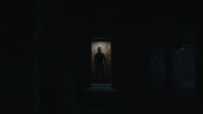 a man standing in a dark room with a creepy look on his face