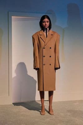 a woman standing in front of a white wall