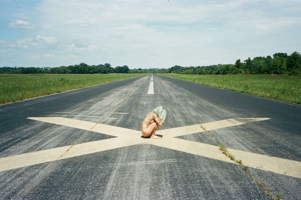 a person sitting on the middle of an empty road