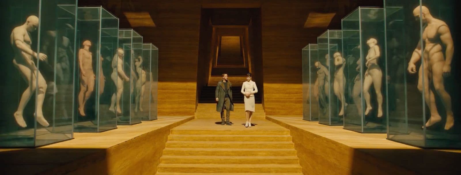two men standing in front of a row of statues