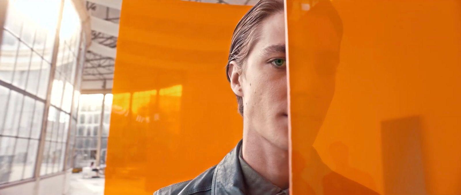 a man standing in front of an orange wall