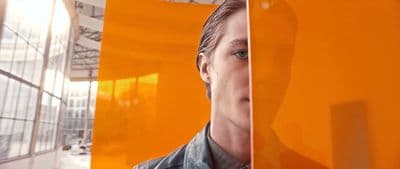 a man standing in front of an orange wall