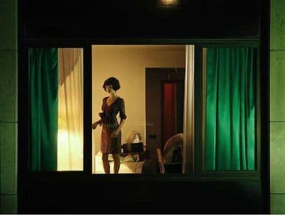 a woman standing in a room with green curtains