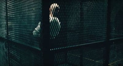 a man standing behind a fence in the dark