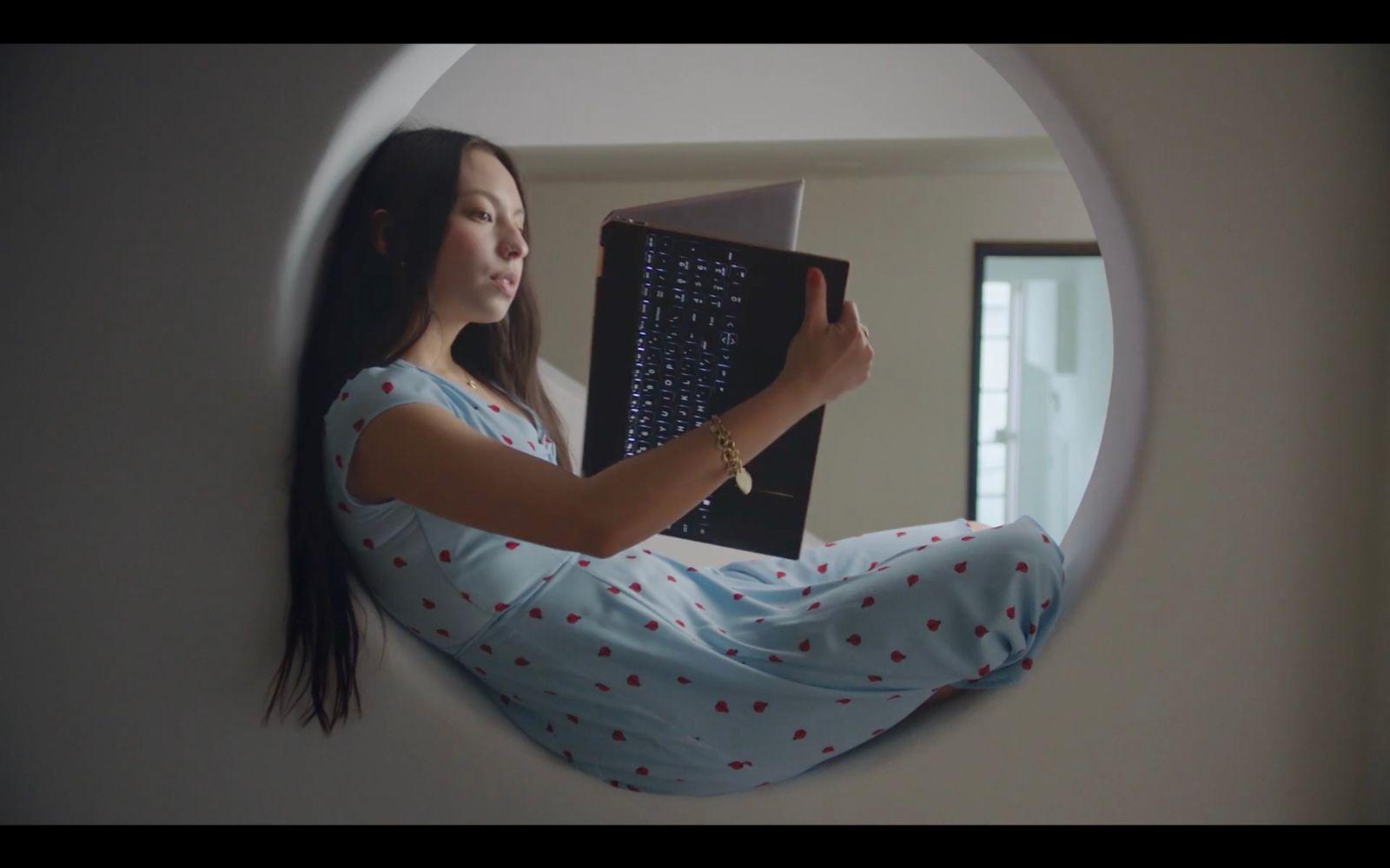a woman sitting on a wall holding a laptop