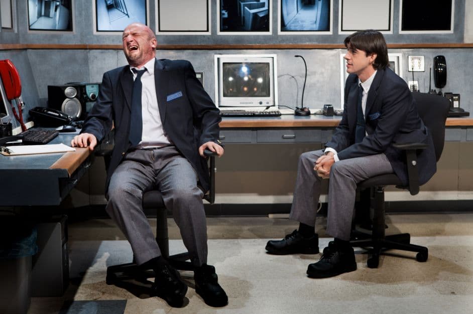 a couple of men sitting in front of a computer desk
