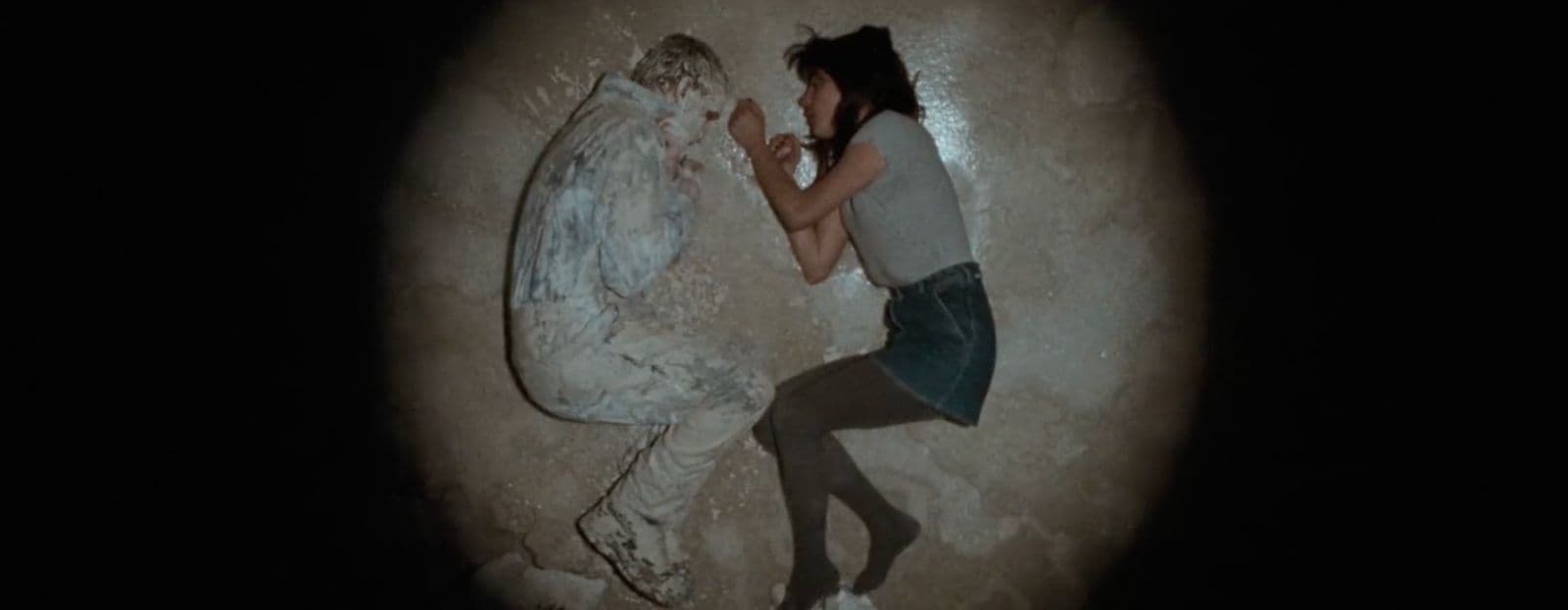 a woman standing next to a statue in the dark