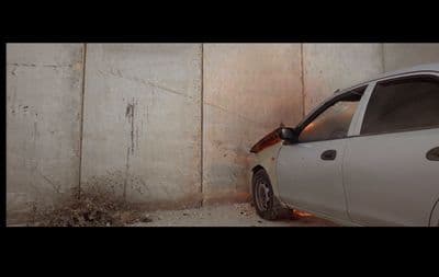 a white car parked next to a concrete wall