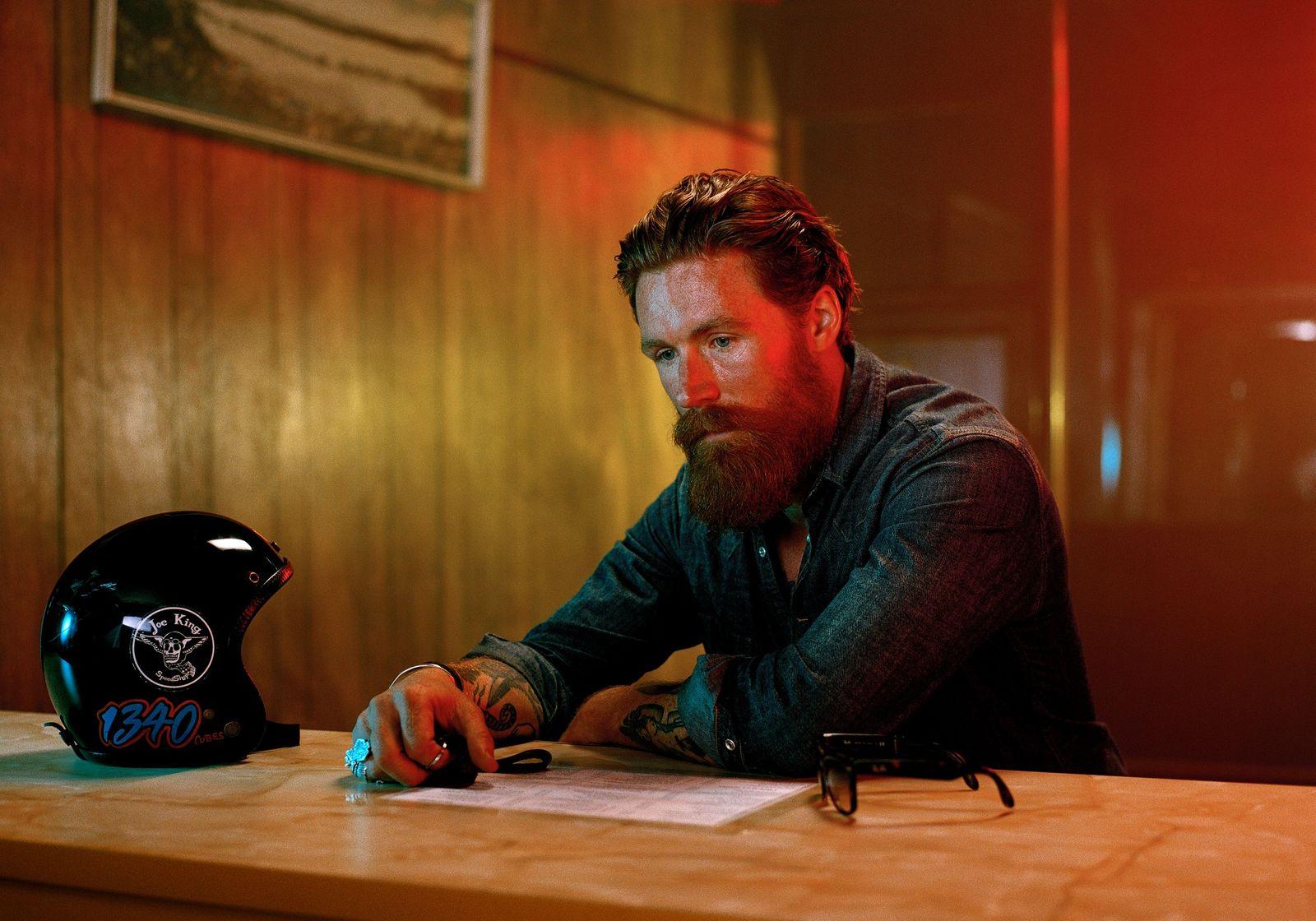 a man sitting at a table with a motorcycle helmet