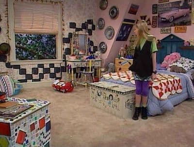 a woman standing in a room with a bed and a dresser