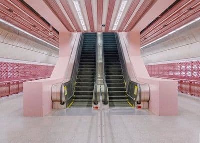 an escalator in a building with pink walls