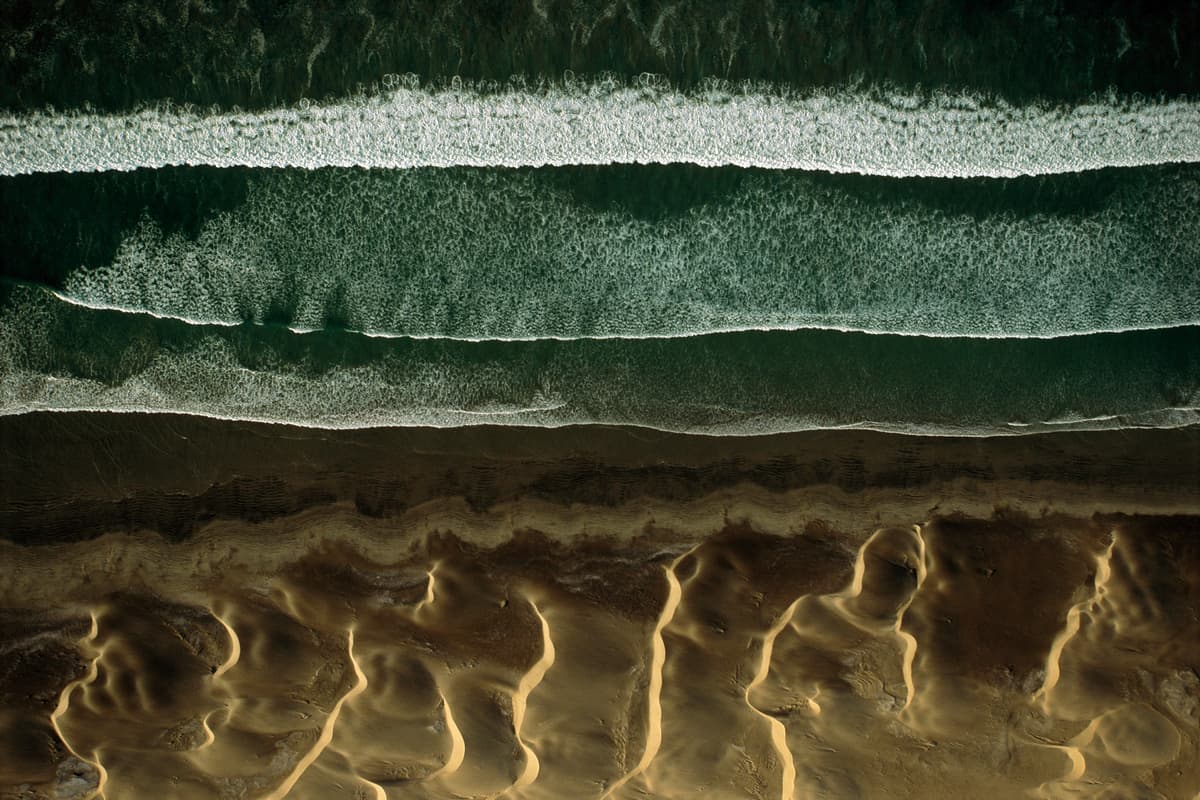 an aerial view of a beach with waves and sand