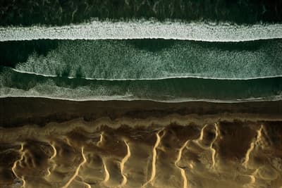 an aerial view of a beach with waves and sand