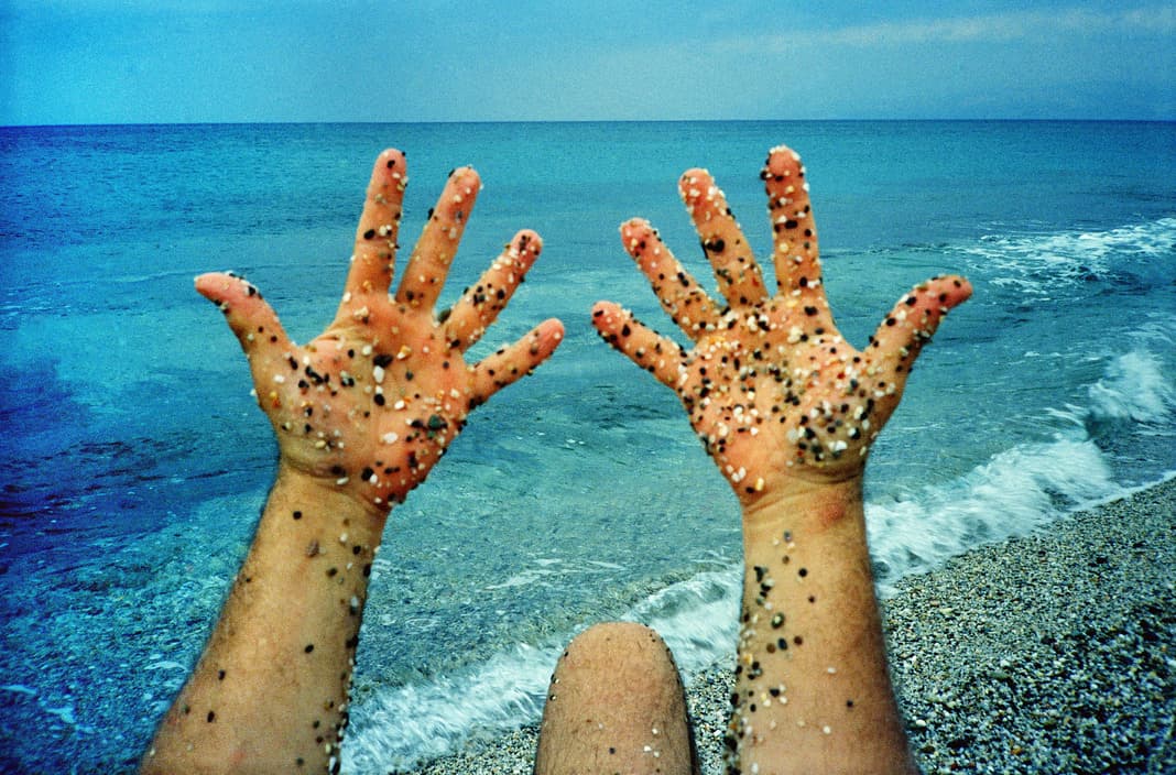 a person's hands covered in sand on the beach