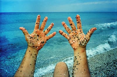 a person's hands covered in sand on the beach