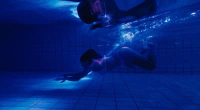 two people swimming under water in a pool